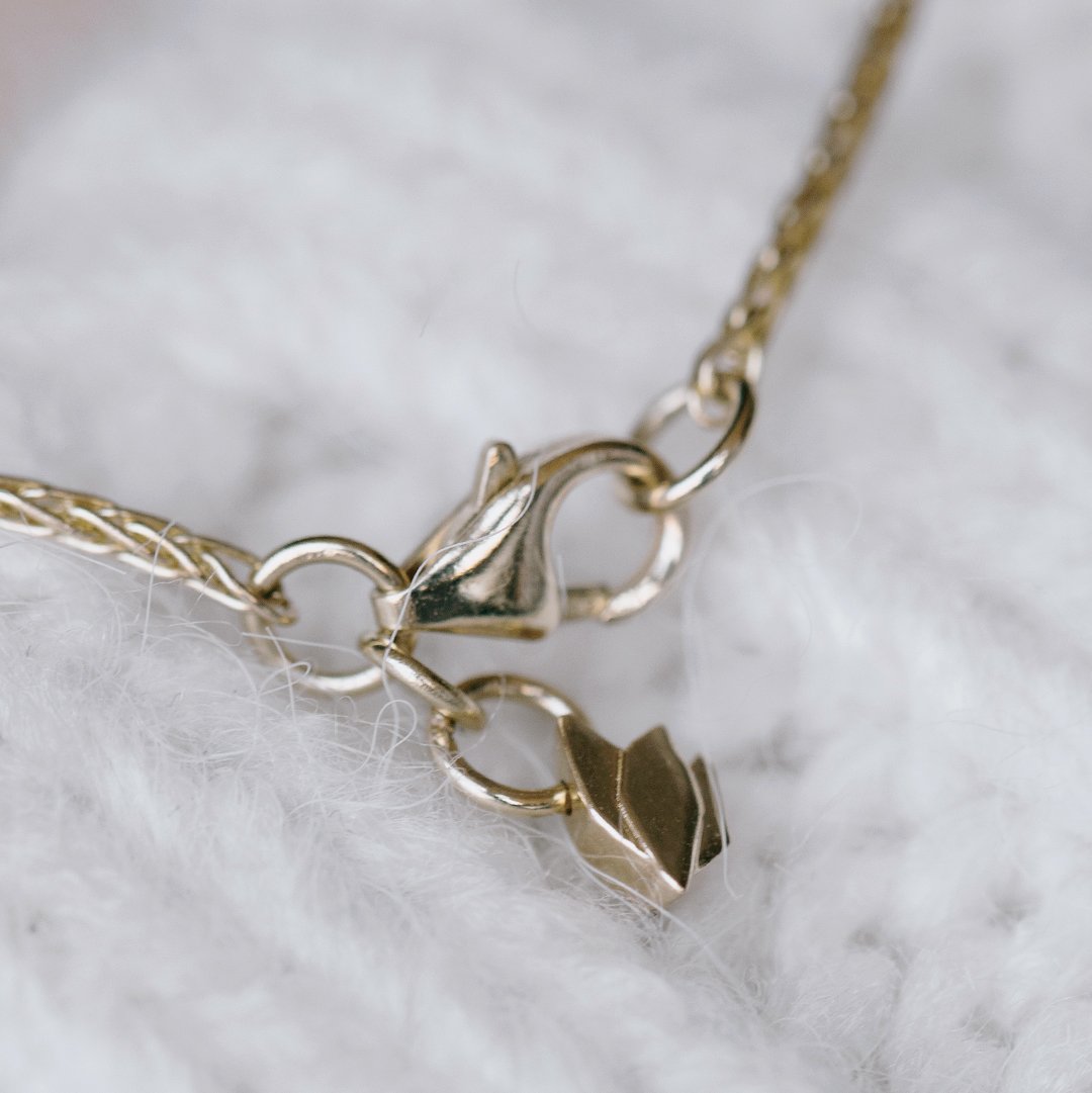 Gold necklace with a cyclamen pendant in a bracket